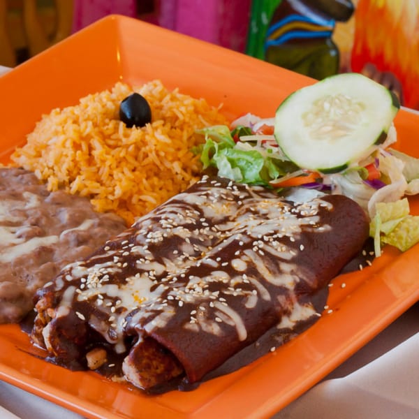 El Coronel Mexican Restaurant's enchiladas with mole sauce, rice, refried beans, and a side salad.